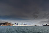 Couverture nuageuse au-dessus des montagnes striées de glace bordant le Kongsfjorden près de Ny-Alesund. Kongsfjorden, île de Spitzberg, Svalbard, Norvège.