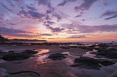 Puddles of water and piles of sand on a beach at sunset. Drake Bay, Osa Peninsula, Costa Rica.
