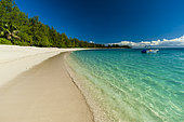 A boat anchored off the shore of a pristine tropical beach. Denis Island, The Republic of the Seychelles.