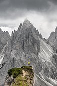 Hiker standing on a ridge, mountain peaks and pointed rocks behind, dramatic cloudy sky, Cimon di Croda Liscia and Cadini group, Auronzo di Cadore, Belluno, Italy, Europe