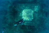 Scuba diver exploring the splendid mosaic (tessellatum) in black and white decorated with a pattern of hexagons, perfectly preserved, Villa a Protiro, Marine Protected Area of Baia, Naples, Italy, Tyrrhenian Sea