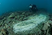 Scuba diver exploring a mosaic of the third century AD, with a maritime theme, made with black and white tiles (tessellatum) depicting a seabed with dolphins, sea urchins, moray eels and other fish, in the thermal complex of Lacus Baianus, Marine Protected Area of Baia, Naples, Italy, Tyrrhenian Sea