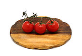 Three red ripe tomatoes on a cutting board on a light background