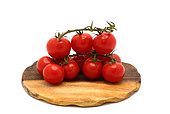 Several red ripe tomatoes on a cutting board on a light background