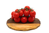 Several red ripe tomatoes on a cutting board on a light background