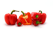 Few red ripe sweet peppers and one pepper in a cut on a light background. Natural product. Natural color. Close-up.