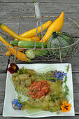 Yellow, green and round courgettes in a basket - Plate containing a dish of melting courgettes with cooked tomatoes and edible flowers of Borage and Nasturtium