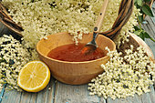 Elderflower (Sambucus) jelly in a wooden bowl, elderflowers, lemon and wooden spoon