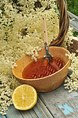 Elderflower (Sambucus) jelly in a wooden bowl, elderflowers, lemon and wooden spoon