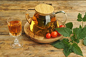 Nettle water, tonic drink for its detox virtues rich in trace elements and mineral salts. Teapot and stemmed glass, cherry tomato and nettle leaves (Urtica sp)