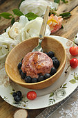 Homemade ice cream with garden cherries and blueberries in a wooden bowl, country atmosphere: wooden table, country plate, rose and lace