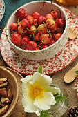 Cerises Napoléon dans un bol blanc et assiette à motifs végétaux dans les tons rouges