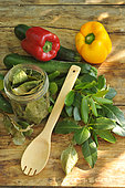 Sweeet bay (Laurus nobilis), dried bay leaves in a transparent jar and freshly cut branches, courgettes and peppers, wooden spoon on a wooden table. Benefits: antioxidant - potassium - magnesium - phosphorus - vitamin C - antiseptic-antibacterial