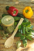 Sweeet bay (Laurus nobilis), dried bay leaves in a transparent jar and freshly cut branches, courgettes and peppers, wooden spoon on a wooden table. Benefits: antioxidant - potassium - magnesium - phosphorus - vitamin C - antiseptic-antibacterial