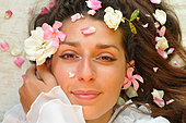 Beauty through plants, roses and oleander flowers on the face of a brunette woman