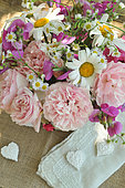 Bouquet of garden flowers: daisies, roses, sweet peas, asters, hearts and lace for decoration