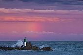 Waves breaking on the port light of the south entrance of the port of Sète at sunset, Hérault, Languedoc-Roussillon, France