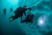 Scuba divers diving around the underwater part of a iceberg, Antarctic Peninsula, Antarctica