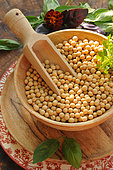Soybeans (Glycine max) in a wooden pan with Sweet basil (Ocimum basilicum) leaves