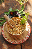 Soybeans (Glycine max) in a wooden pan with Sweet basil (Ocimum basilicum) leaves