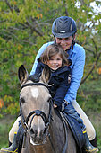 Woman rider with a little girl on a New Forest stallion - family and horses