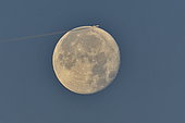 Full moon and long-haul aircraft appearing to skim the star, Doubs, France
