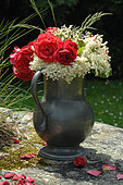 Bouquet of flowers outdoors, Red Roses (Rosa sp) and Elder flowers ( Sambucus sp), in a pewter pot