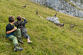 Children watching Alpine Ibex (Capra ibex) in the French Alps.