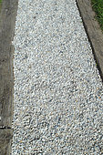 Garden path with white pebbles, borders made of railway sleepers