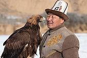 Kyrgyz eagler (Berkutchi) with a Kalpak, carrying its eagle, Yssyk Kul, Kyrgyzstan