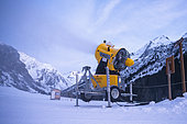 Snow cannon operating at night in the mountains as soon as negative temperatures arrive in order to maintain the snow on the cross-country ski trails of the Champagny le Haut ski area in the Alps, Champagny-en-Vanoise, France.