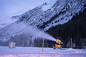 Snow cannon operating at night in the mountains as soon as negative temperatures arrive in order to maintain the snow on the cross-country ski trails of the Champagny le Haut ski area in the Alps, Champagny-en-Vanoise, France.