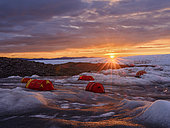 Camp with tents on the ice sheet. The brown sediment on the ice is created by the rapid melting of the ice. Landscape of the Greenland ice sheet near Kangerlussuaq. America, North America, Greenland, danish territory
