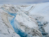 Drainage system on the surface of the ice sheet. The brown sediment on the ice is created by the rapid melting of the ice. Landscape of the Greenland ice sheet near Kangerlussuaq. America, North America, Greenland, danish territory