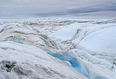 Drainage system on the surface of the ice sheet. The brown sediment on the ice is created by the rapid melting of the ice. Landscape of the Greenland ice sheet near Kangerlussuaq. America, North America, Greenland, danish territory