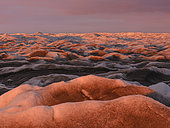 Midnight sun on the ice sheet. The brown sediment on the ice is created by the rapid melting of the ice. Landscape of the Greenland ice sheet near Kangerlussuaq. America, North America, Greenland, danish territory