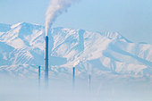 Smoke and chimneys, pollution in Bishkek with mountains in the background, Kyrgyzstan