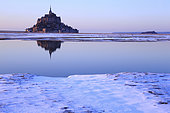 Mont-Saint-Michel under the snow in winter seen from the polder at sunset, Normandy, France