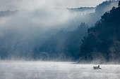 Boat on the Vouglans Lake in the mist, Jura, France