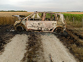 Véhicule incendié sur un chemin de campagne entre un champ de blé et un vignoble bio. Loir et Cher, France