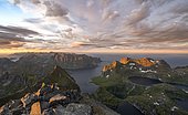 View over mountain peaks and sea, dramatic sunset, mountaineers at Hermannsdalstinden, with lakes Litlforsvatnet and Tennesvatnet and fjord Forsfjorden, Moskenesöy, Lofoten, Nordland, Norway, Europe