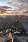 View over mountain peaks and sea, dramatic sunset, mountaineers at Hermannsdalstinden, with fjord Forsfjorden, Moskenesöy, Lofoten, Nordland, Norway, Europe