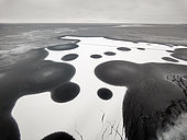 Strange pattern covering a young translucent ice pack (or black nilas). A black circle appears on the fresh snow where a hole in the nilas has allowed water to diffuse uniformly into the thin snow cover by capillary action, Isfjord, Spitsbergen, Svalbard archipelago.