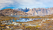 Reflection in a small lake surrounded by autumn-colored tundra of a mountain landscape in Scoresby Sound, Greenland