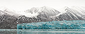 Bluish Monaco glacier against a backdrop of snow-covered mountains north of the island of Spitsbergen, Svalbard archipelago.