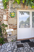 Sloping lane and facade of a brick house with the Gites de France sign, round metal badge, Penne d'Agenais, France.