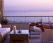 IN*Grèce, Paros, femme allongée sur table de massage sur balcon d'une suite de l'hôtel Asterias, mer au fond, coucher de soleil