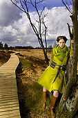 IN*Jeune femme posant appuyée contre arbre, manteau vert, bottes
