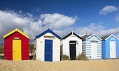 England, Suffolk, Southwold. A line of colourful beach huts on the beach at Southwold.