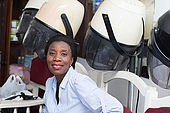 young woman is sitting next helmets waiting her turn for her hairstyle.